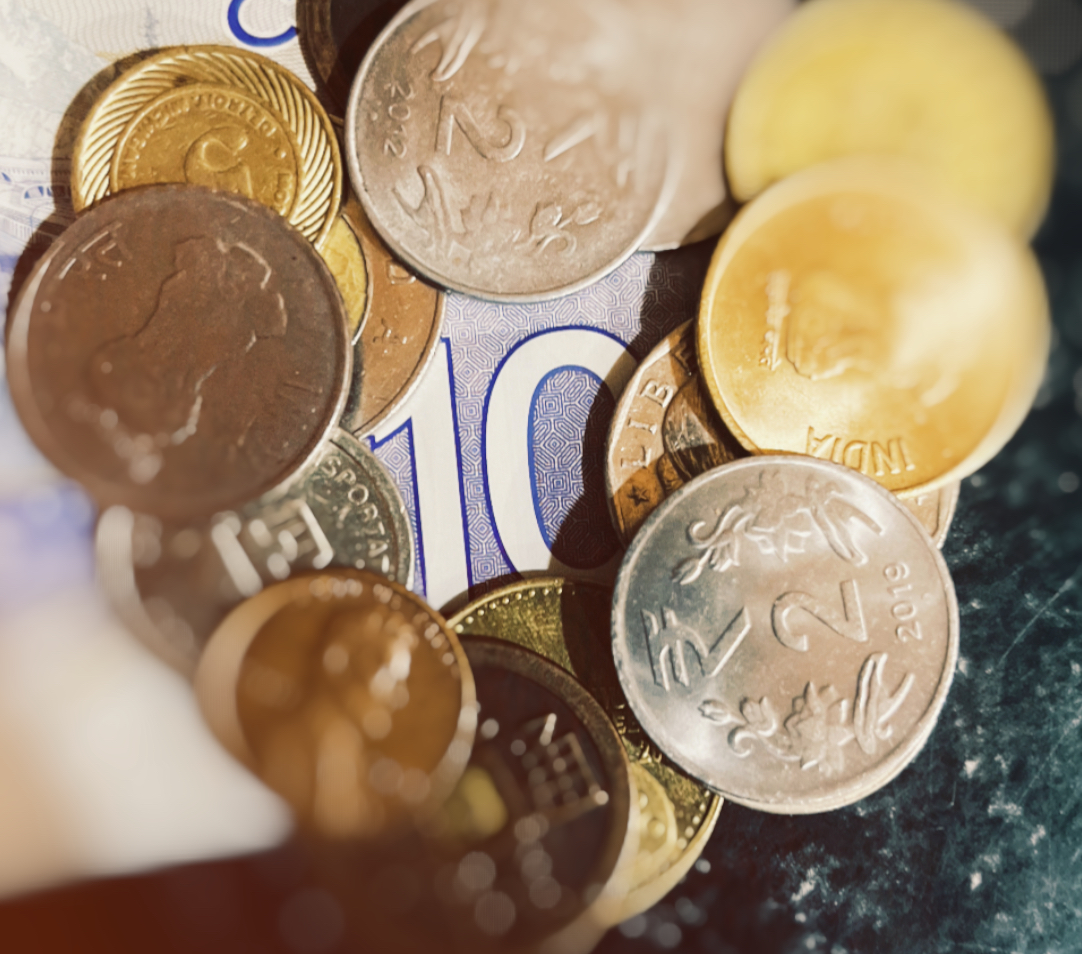 Coins from different countries arranged so that the coins are in a circle around a 10 dollar bill.